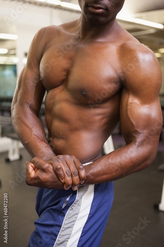 Mid section of a shirtless muscular man in gym