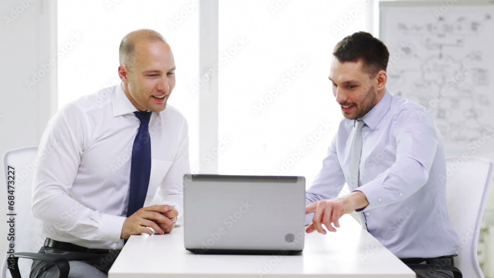 two smiling businessmen with laptop in office two smiling businessmen with laptop in office