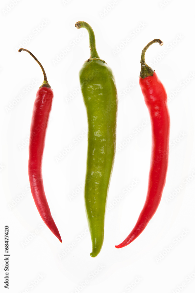 one green and two red peppers on a white background