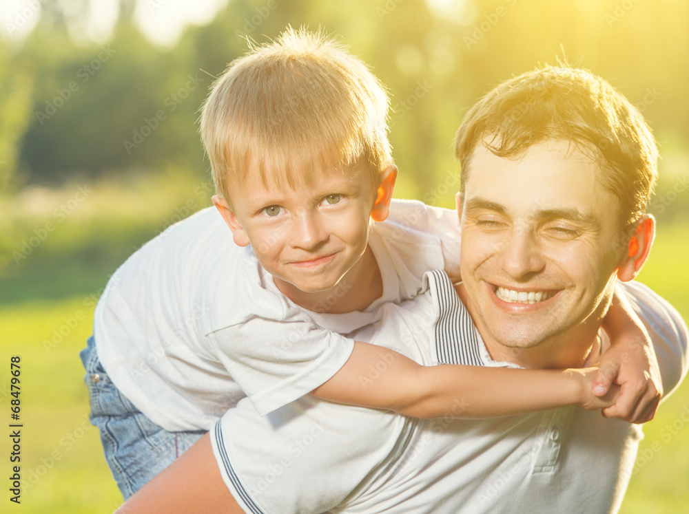 Fototapeta premium happy Dad and son hugging and laughing in summer nature