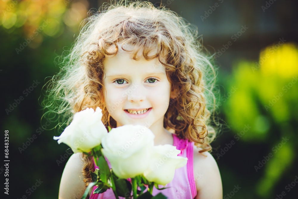Curly baby with flowers in her hand. Toning photo. Curly baby with flowers in her hand. Toning photo.