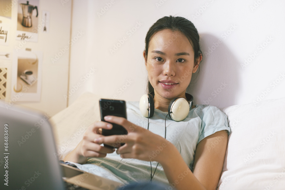 Casual young woman sitting on bed and using smart phone at home. Casual young woman sitting on bed and using smart phone at home.