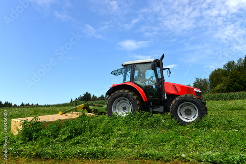 Organic farmer in tractor mowing clover field with rotary cutter