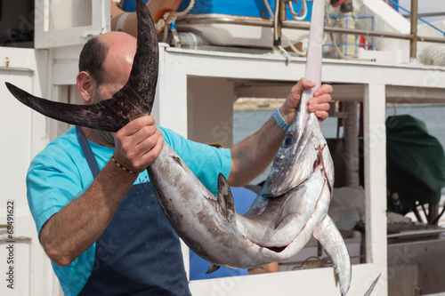 Man holding swordfish at sea port
