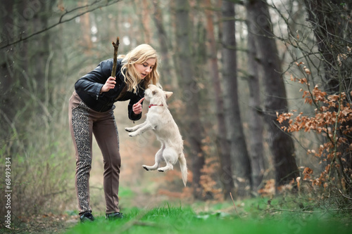 Blond girl playing with her puppy in the forest © wrzesientomek