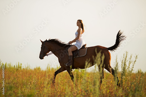 Young woman riding a brown horse