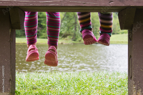 Little feet hanging from a bench at a pond
