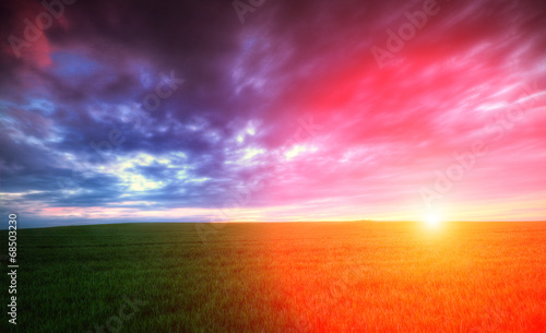 Zachód słońca na zielonym polem z chmurami