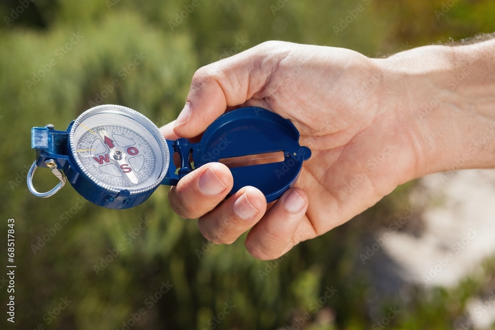 Hiker holding his compass in the countryside Hiker holding his compass in the countryside