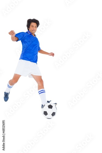 Fototapeta Naklejka Na Ścianę i Meble -  Football player in blue kicking ball