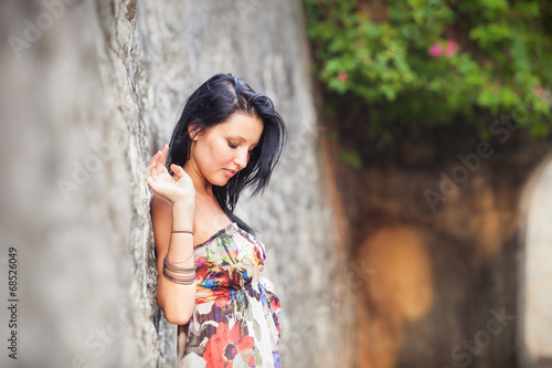 beautiful brunette girl posing near rock wall
