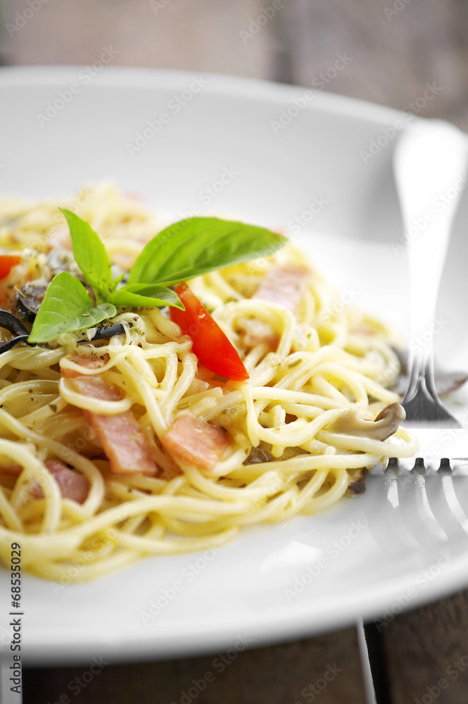 close up spaghetti and bacon fried in white dish