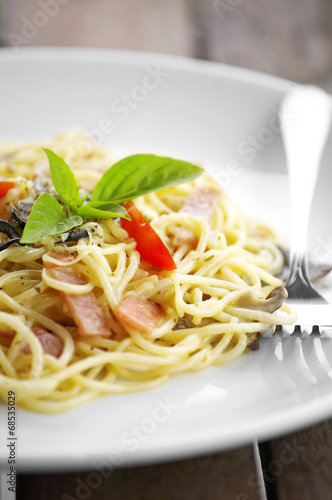 close up spaghetti and bacon fried in white dish