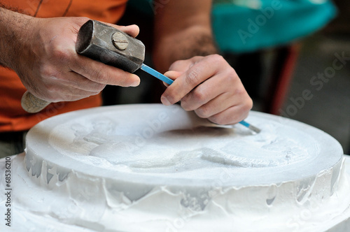 Stone mason at work carving an ornamental relief