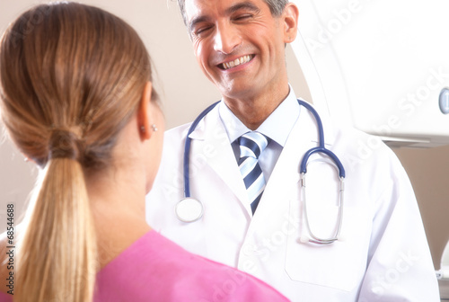 Happy young male doctor speaking with female patient undergoing