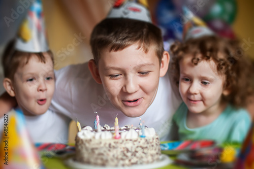boy blows out the candles on a birthday cake and hugs his brothe
