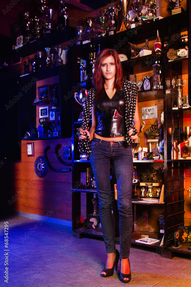  Biker girl standing in front of many trophies.