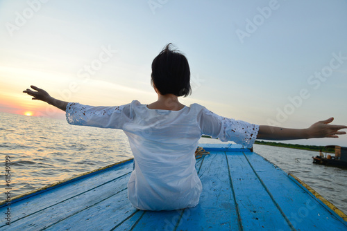 Woman traveling by wood boat at sunset among the islands