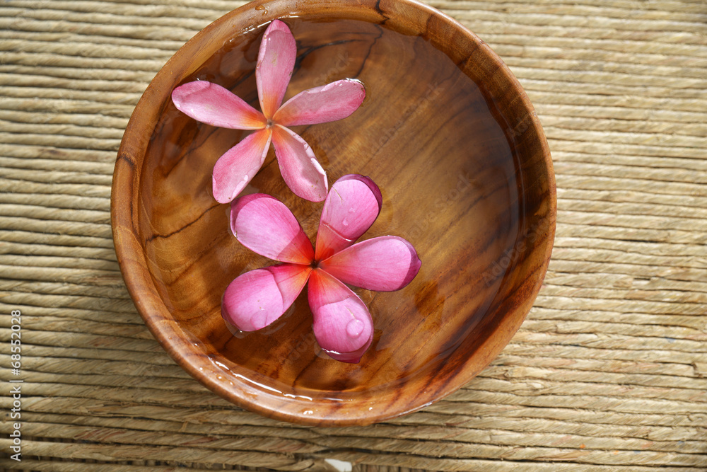 frangipani in water wooden bowl on Brown straw mat frangipani in water wooden bowl on Brown straw mat