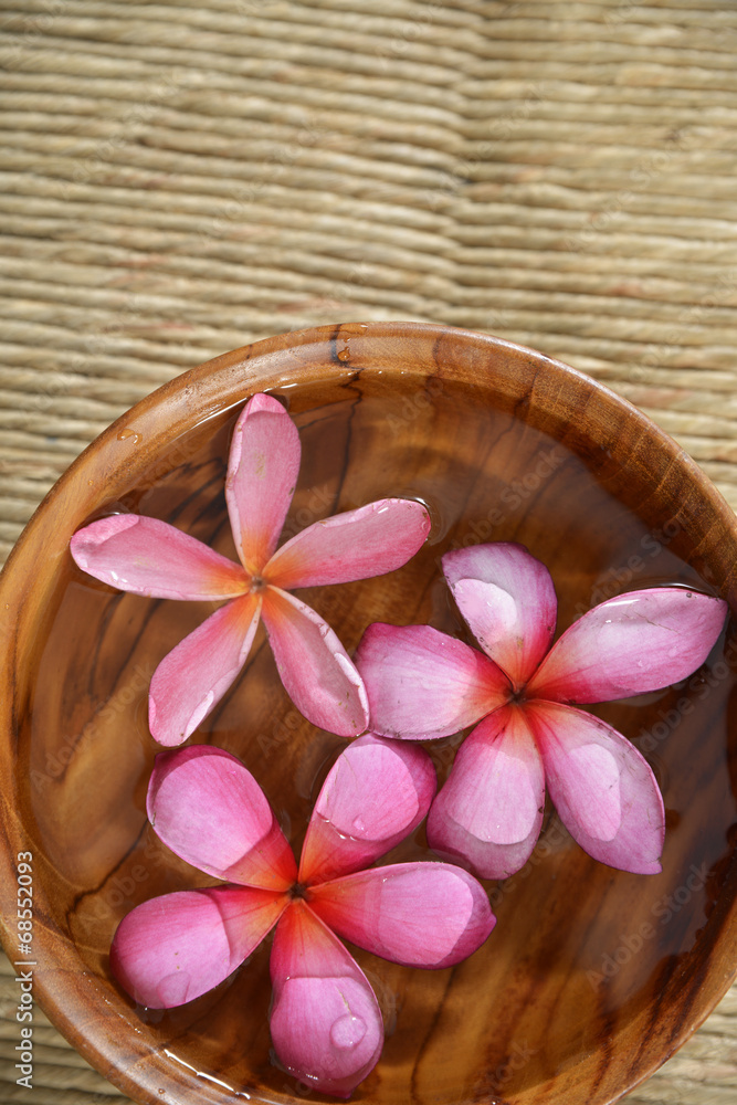 frangipani in water wooden bowl on Brown straw mat frangipani in water wooden bowl on Brown straw mat