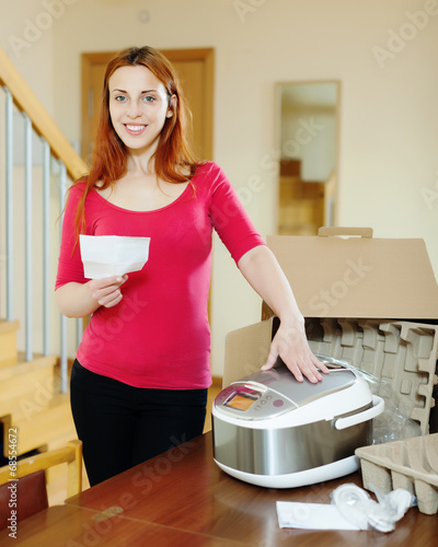 cheerful woman  reading manual for new slow cooker photo