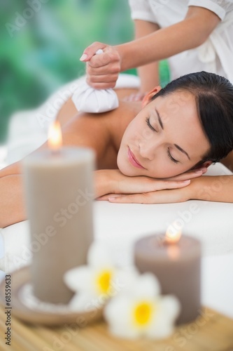 Beautiful brunette enjoying a herbal compress massage