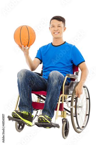 hopeful young man sitting on a wheelchair with a basketball
