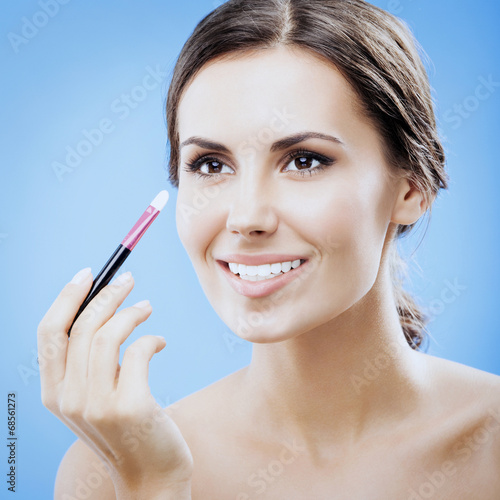 Woman with cosmetics brush, on blue