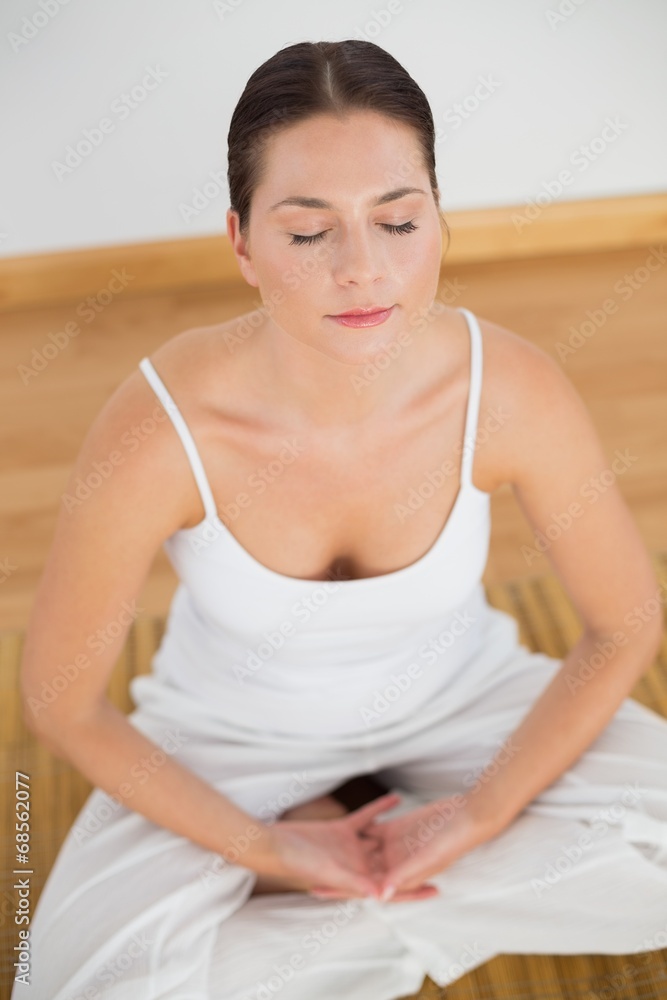 Woman sitting in lotus pose with eyes closed Woman sitting in lotus pose with eyes closed