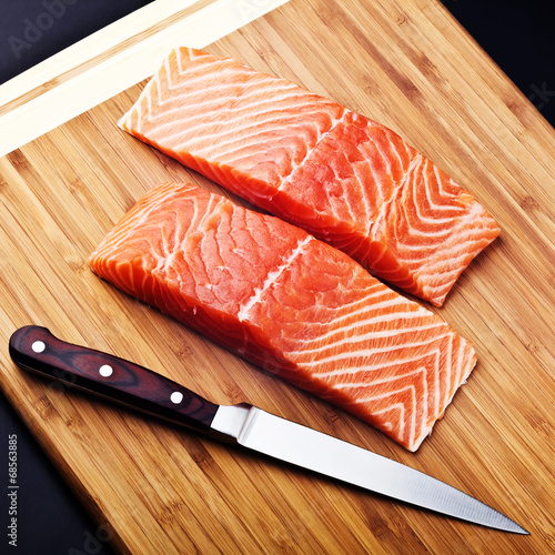 salmon fillet with knife on wood board