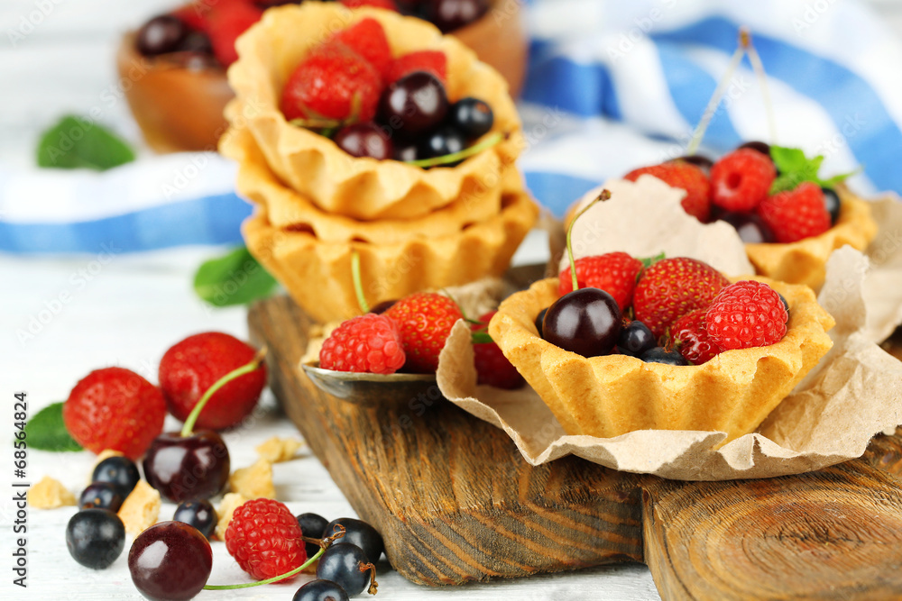 Tasty tartlets with berries on wooden table Tasty tartlets with berries on wooden table