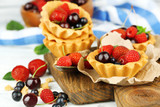 Tasty tartlets with berries on wooden table