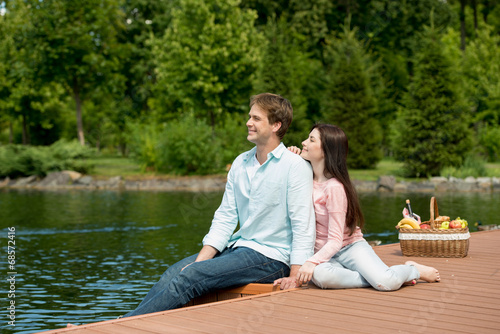 Happy romantic couple enjoying picnic in a park near lake