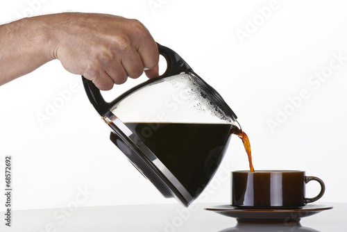 Obraz na płótnie man's hand holding and pouring coffee into a brown cup