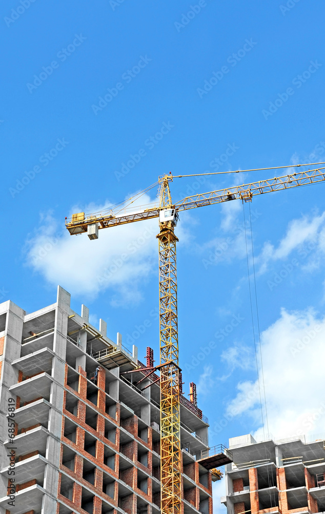 Crane and building construction site against blue sky