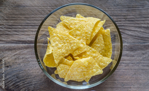 Heap of corn chips in the glass bowl on the wooden background