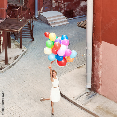 beautiful lady in retro outfit holding a bunch of balloons betwe photo