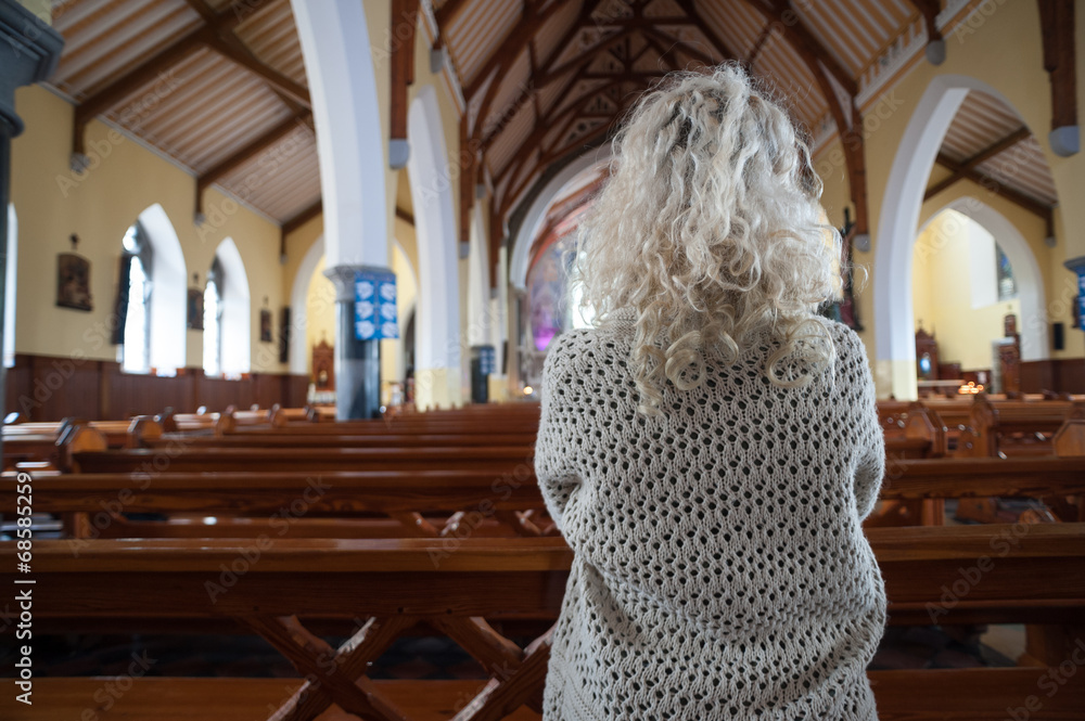 woman praying in church from behind - obrazy, fototapety, plakaty 
