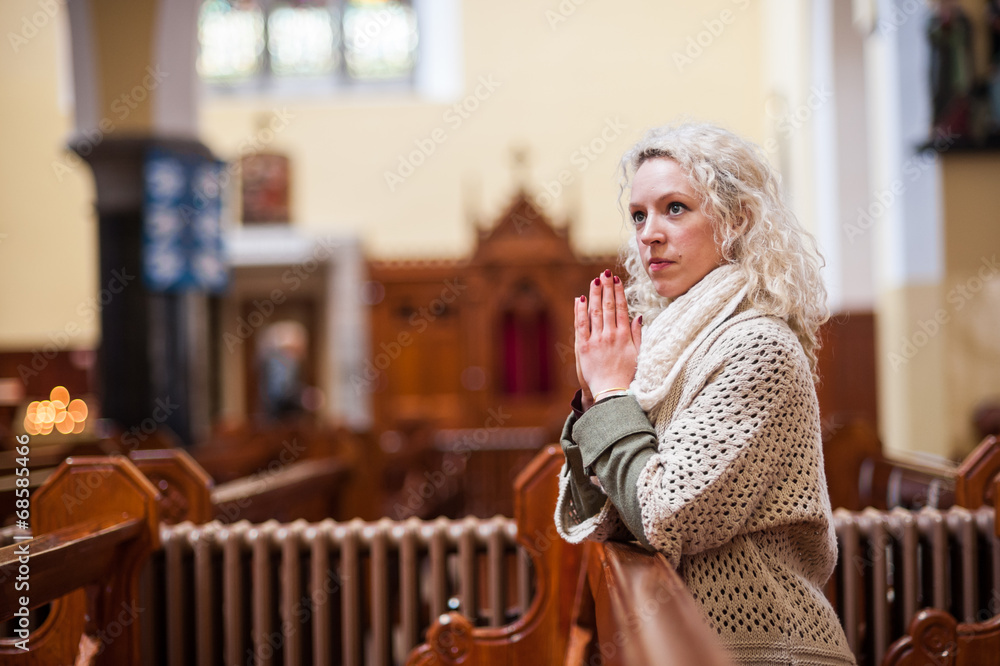 young woman praying in church - obrazy, fototapety, plakaty 