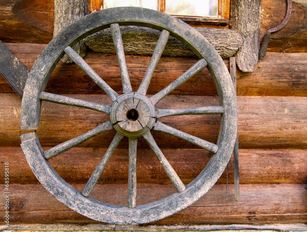 Hand spinning wheel on  wall of  old log house