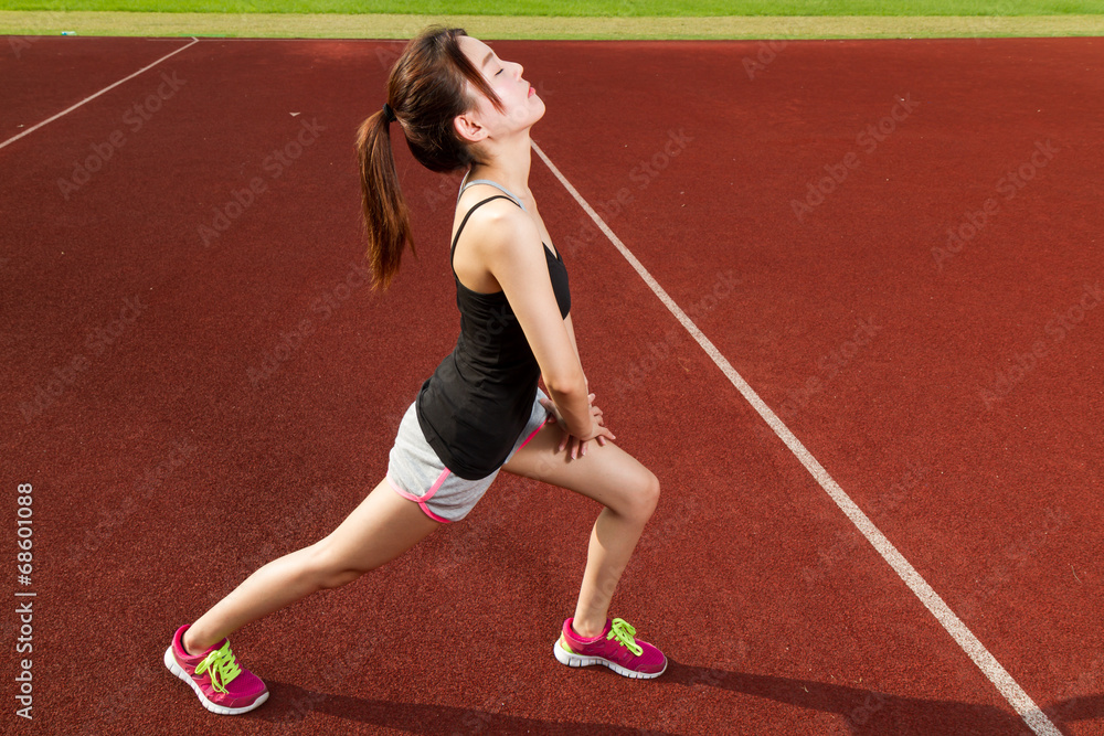 Chinese female athelete stretching legs on sports field, warming