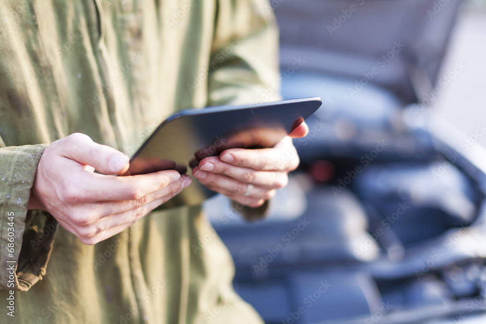 © Mikko Lemola - Mechanic using tablet computer wearing overalls under open hood © Mikko Lemola - Mechanic using tablet computer wearing overalls under open hood
