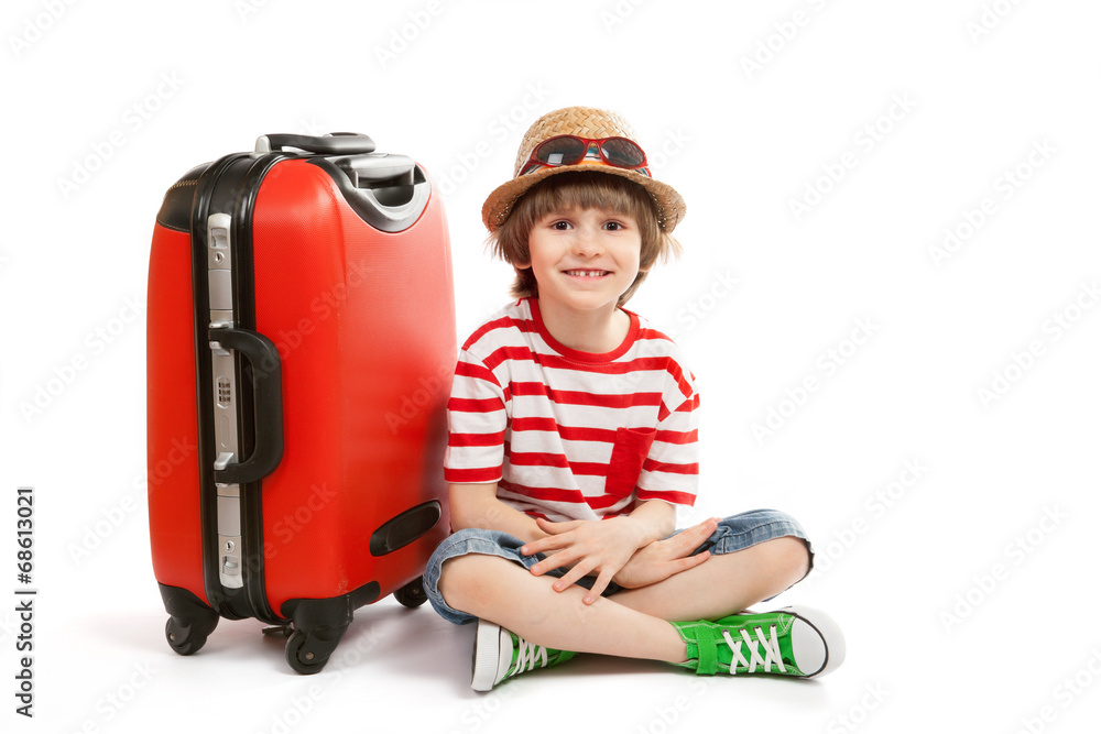 Joyful small boy sits at red suitcase Joyful small boy sits at red suitcase