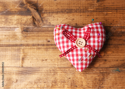 Fabric heart with color pins on wooden background