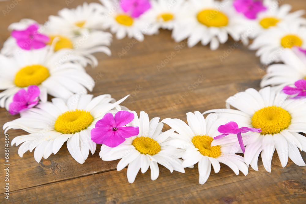 Obraz premium Chamomile wreath on brown wooden background