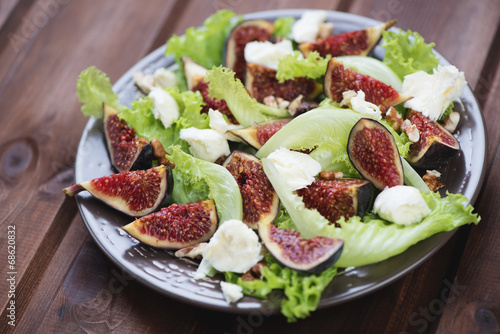 Glass plate with fig fruits, cheese and walnuts salad, close-up