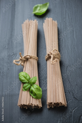 Raw buckwheat soba noodles with green basil, studio shot