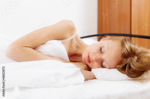 Blonde girl sleeping on white sheet