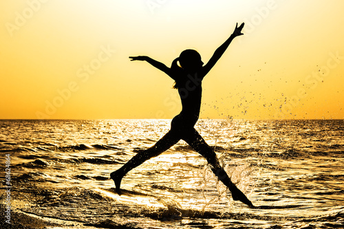The silhouette of a girl  running along the seashore  at sunset