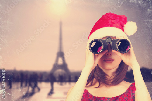 Girl with binocular and christmas hat and parisian background. © Masson